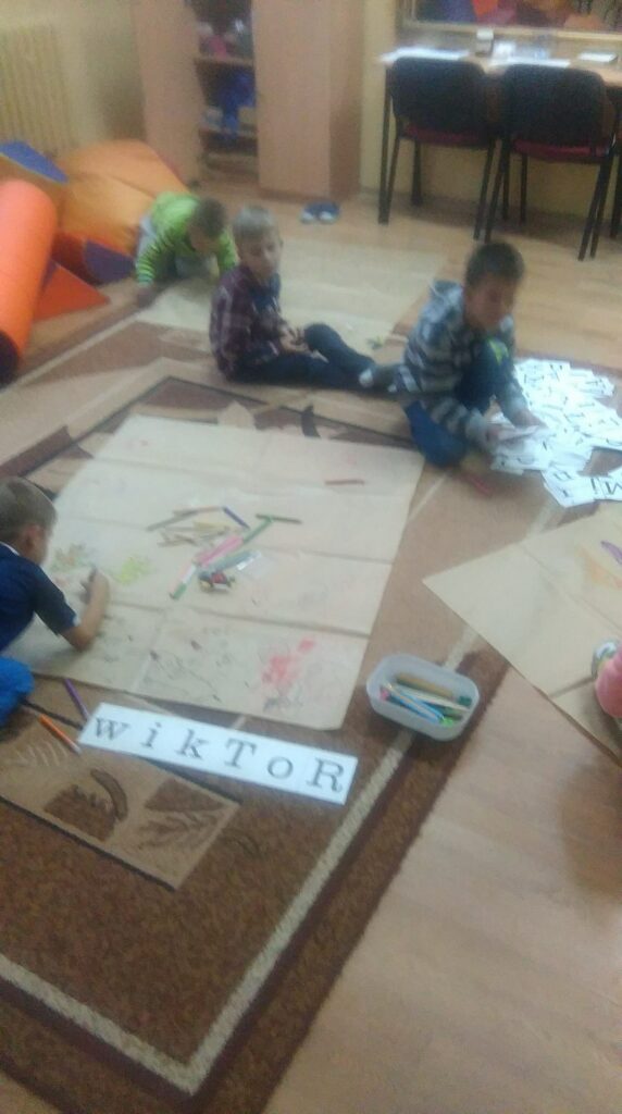 Uczniowie układają napisy na podłodze
