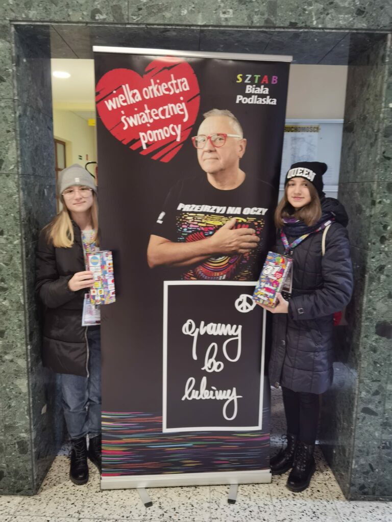 Uczniowie pozujący przy plakacie przedstawiającym Jurka Owsiaka