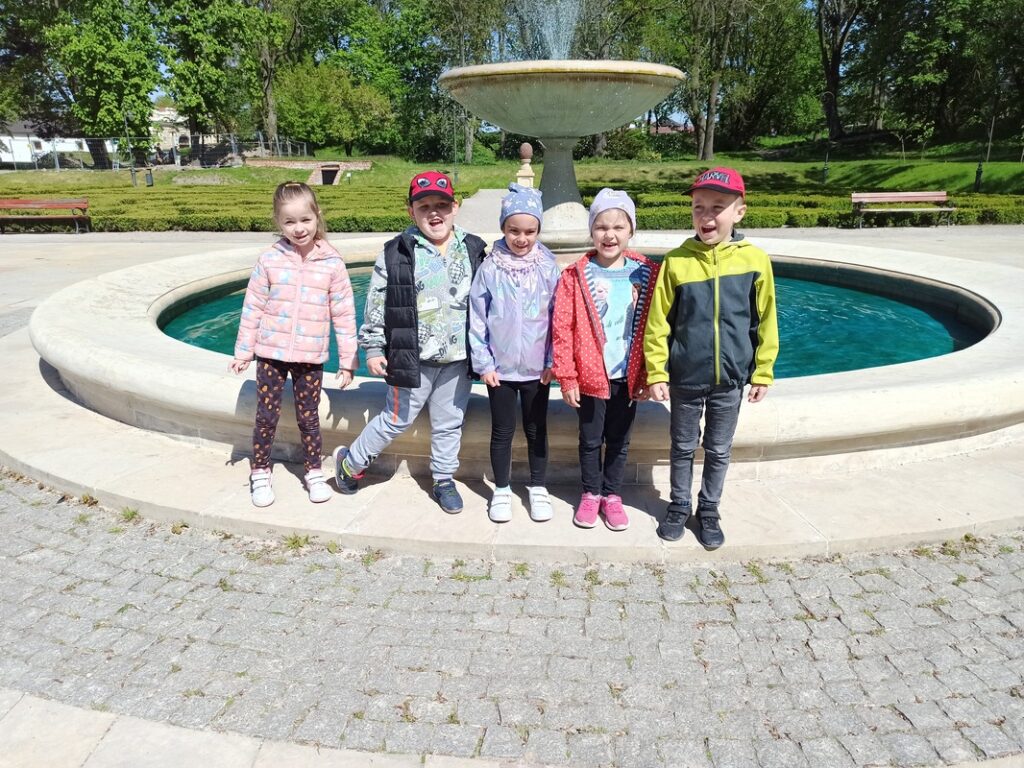 Dzieci stoją przed fontanną.