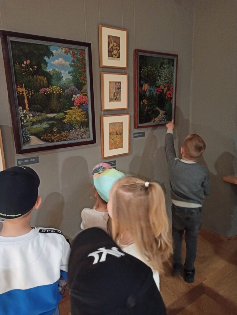 Dzieci oglądają kwiaty na obrazach.