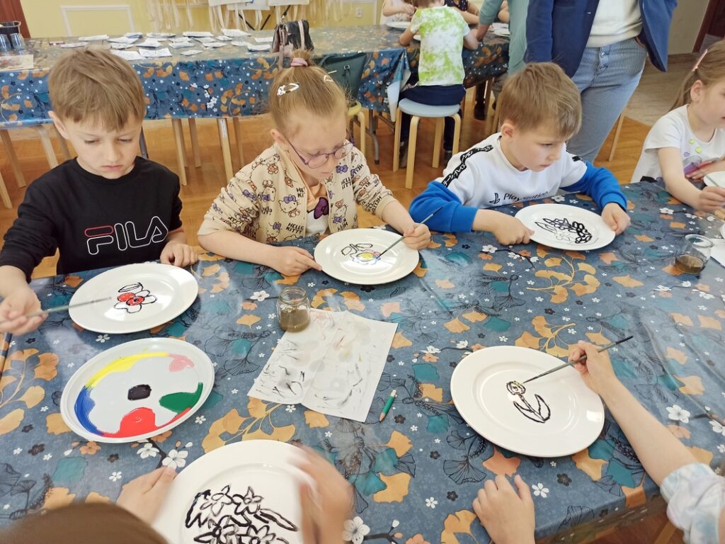 Dzieci malują farbami do ceramiki. 