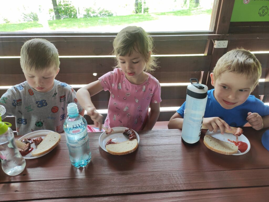 Dzieci jedzą kiełbaskę.