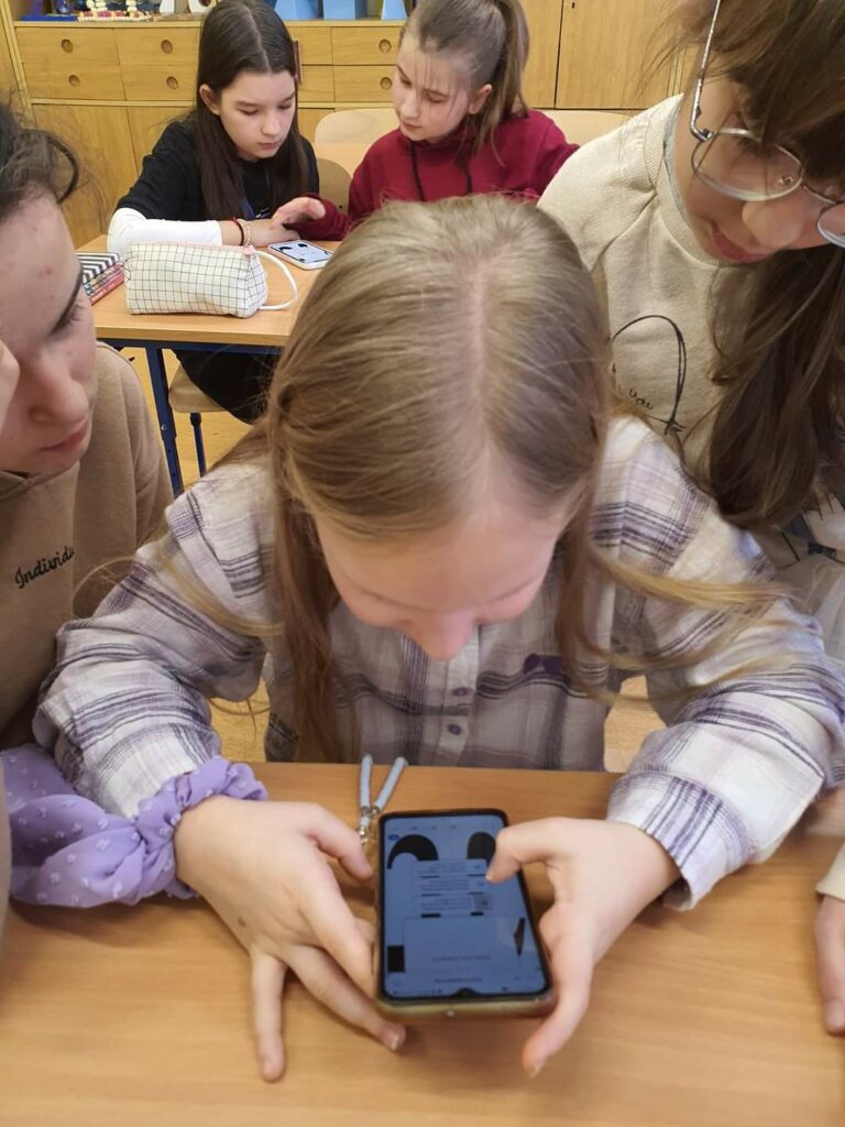 Dwie dziewczynki przy pomocy smartfonu rozwiązują zagadki matematyczne
