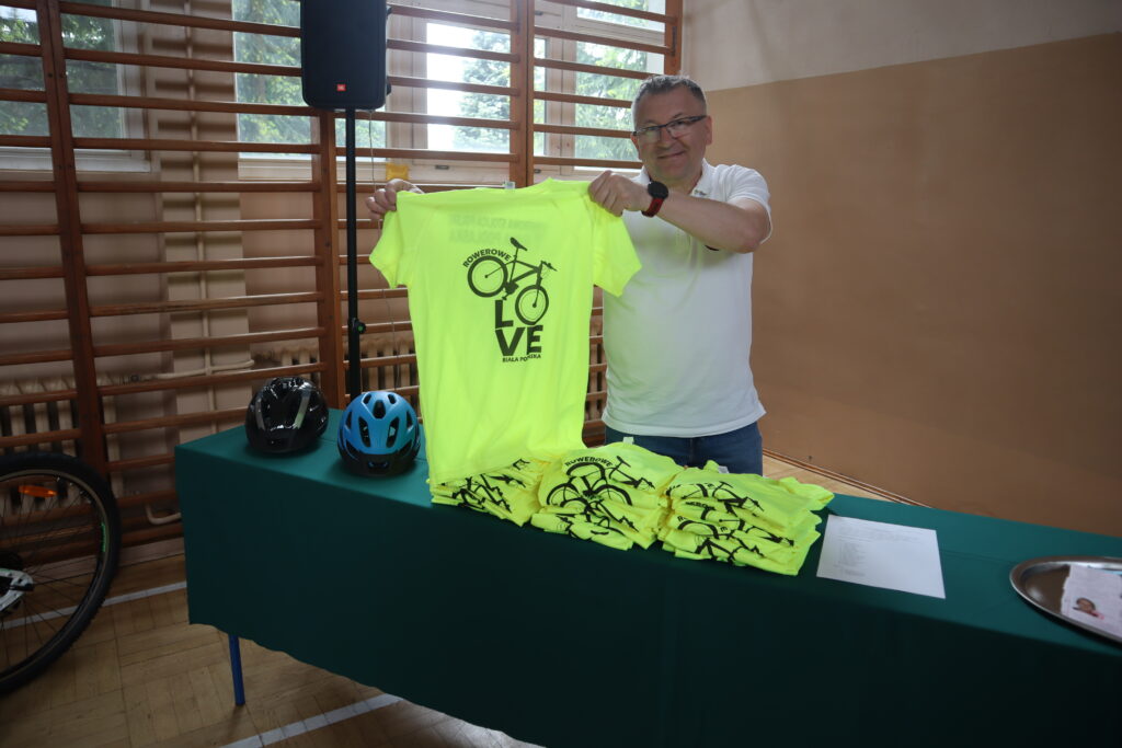 Pracownik urzędu miasta pokazujący koszulki rowerowe, które były wręczane uczniom