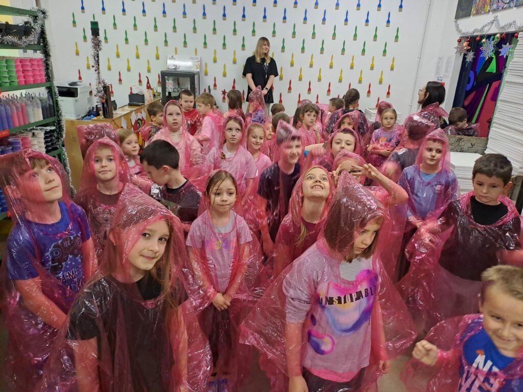 Dzieci ubrane w ochraniacze na ubrania, gotowe do zabawy farbami