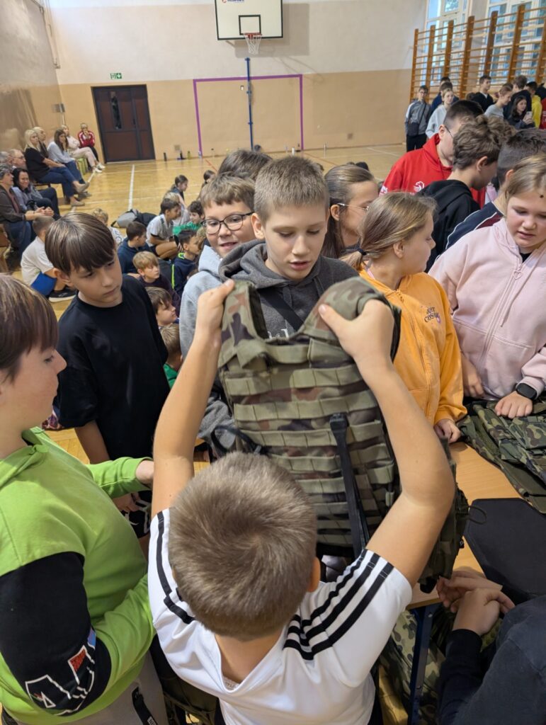 Uczeń prezentuję kamizelkę taktyczną swoim kolegom