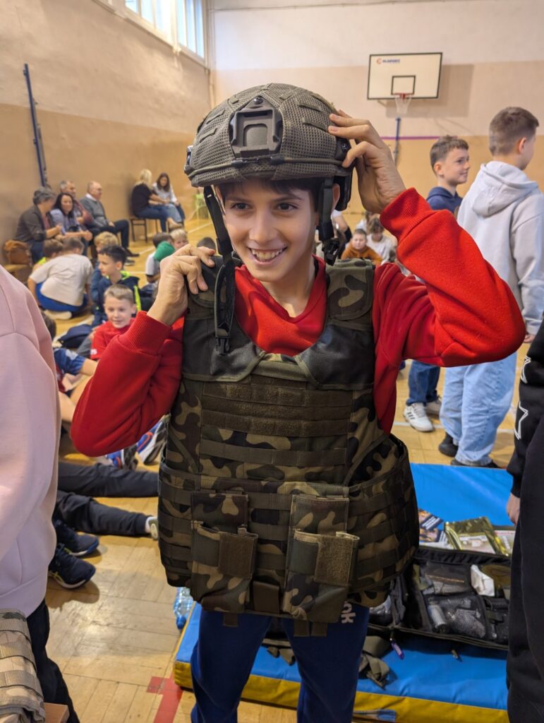 Uczeń prezentuje hełm i kamizelkę taktyczną