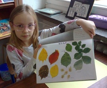 Uczennica pokazuje zdjęcia jesiennych liści