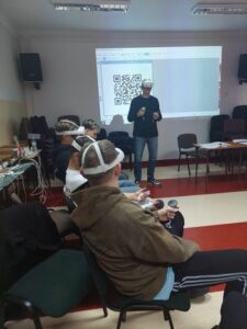 prowadzący zajęcia w goglach vr stoi a uczniowie w goglach siedzą