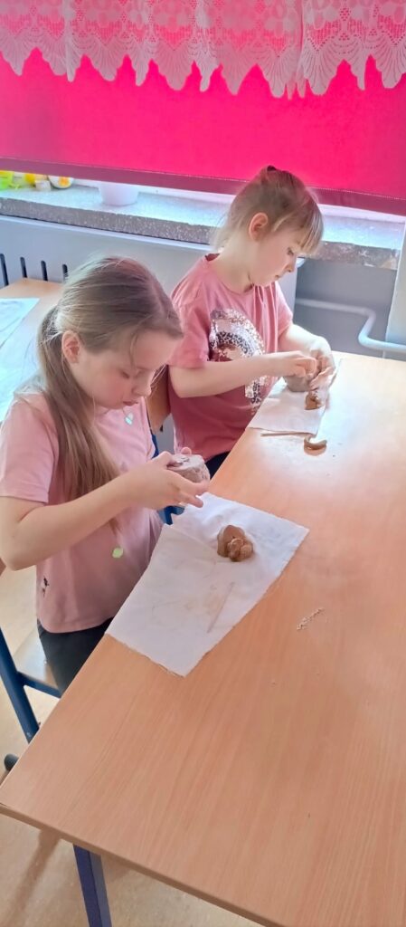 Uczennice formują z gliny naczynia