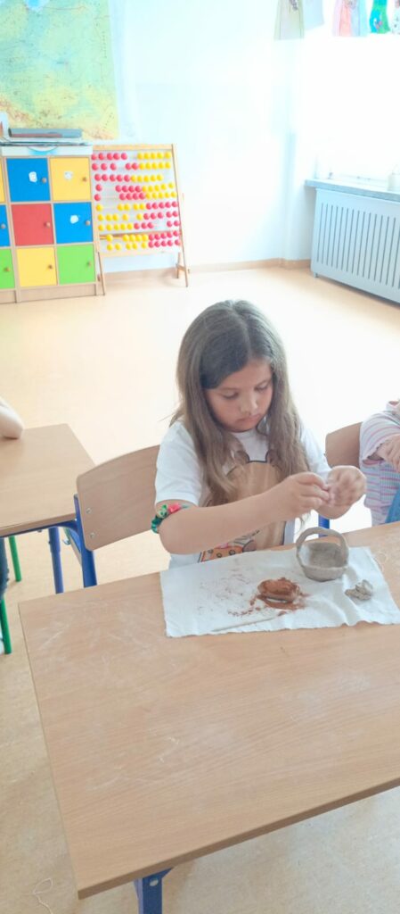 Uczennica wykonuje ozdoby do naczynia z gliny