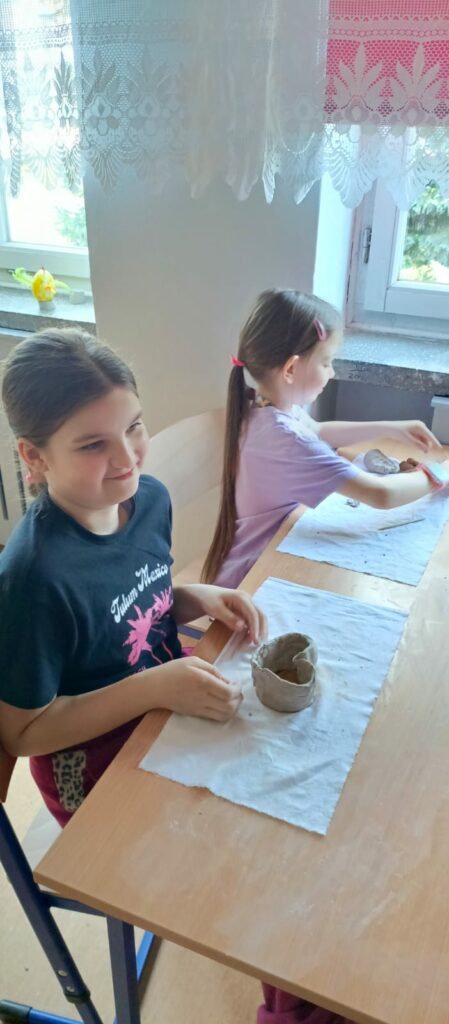 Uczennica prezentuje pracę z gliny