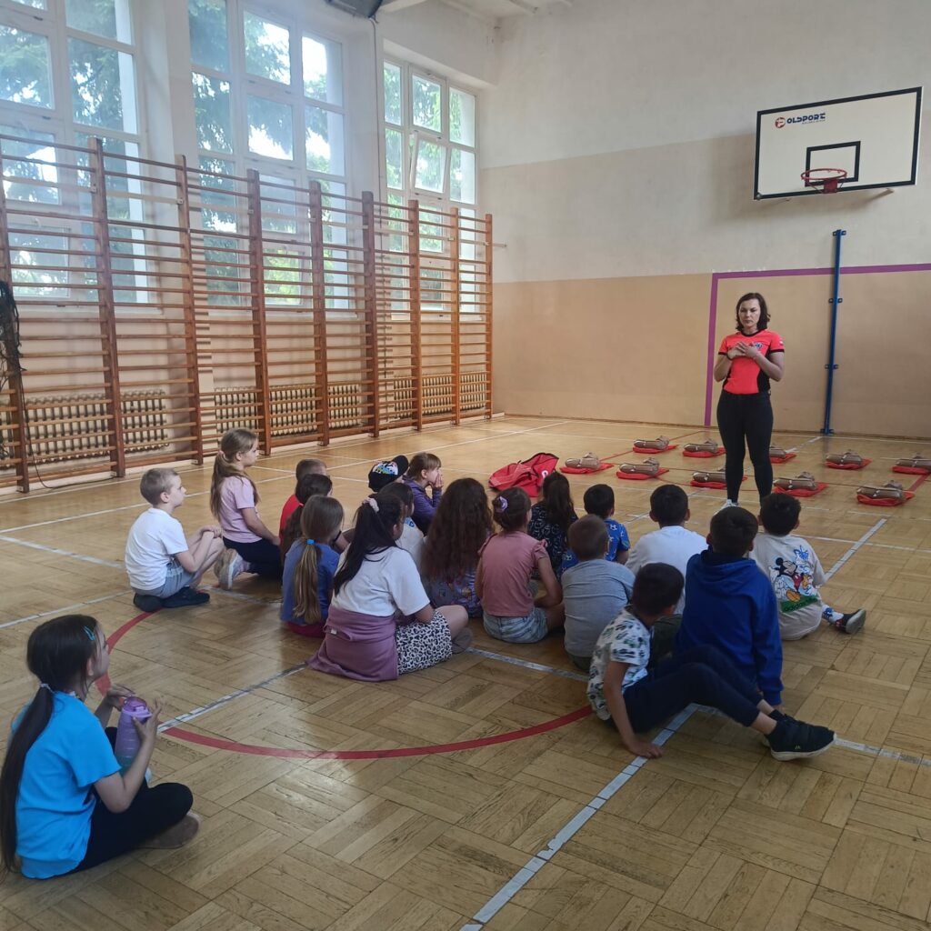 Uczniowie słuchają objaśnień instruktora pierwszej pomocy