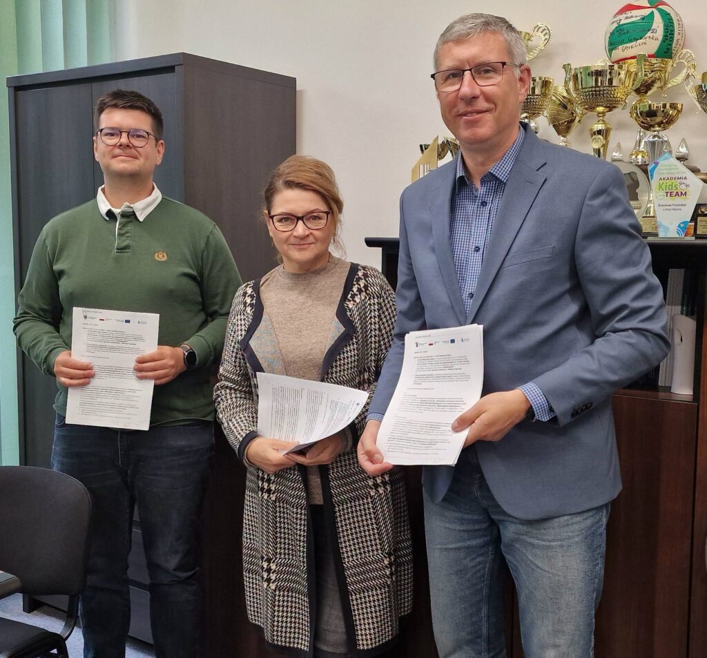 2 mężczyzn i kobieta stoją trzymając przed sobą dokumenty